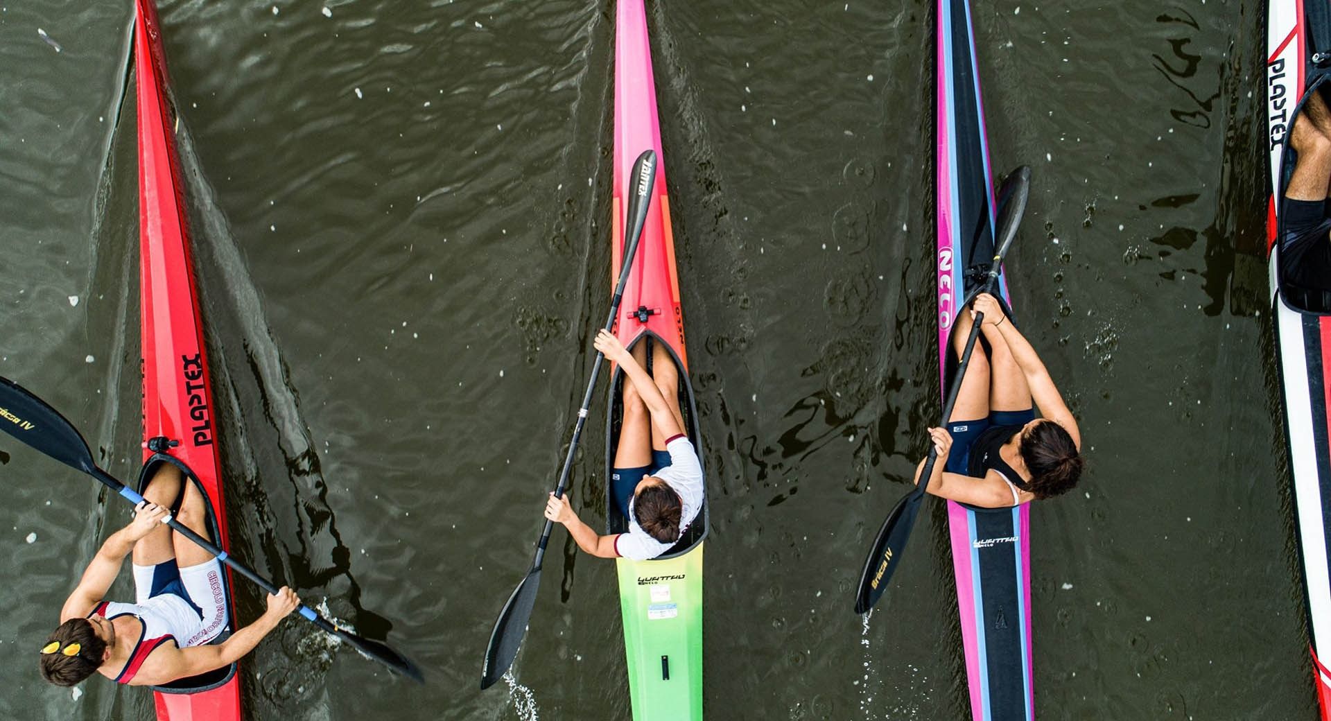 Tre kayak da gara visti dall'alto sull'acqua scura, un atleta con la canottiera del Circolo Nautico Oristano