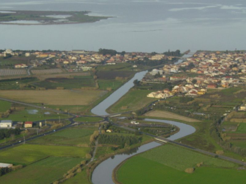 Veduta aerea di Cabras con il canale del Rio Tanui che sfocia nello stagno, il centro canoa e le campagne intorno