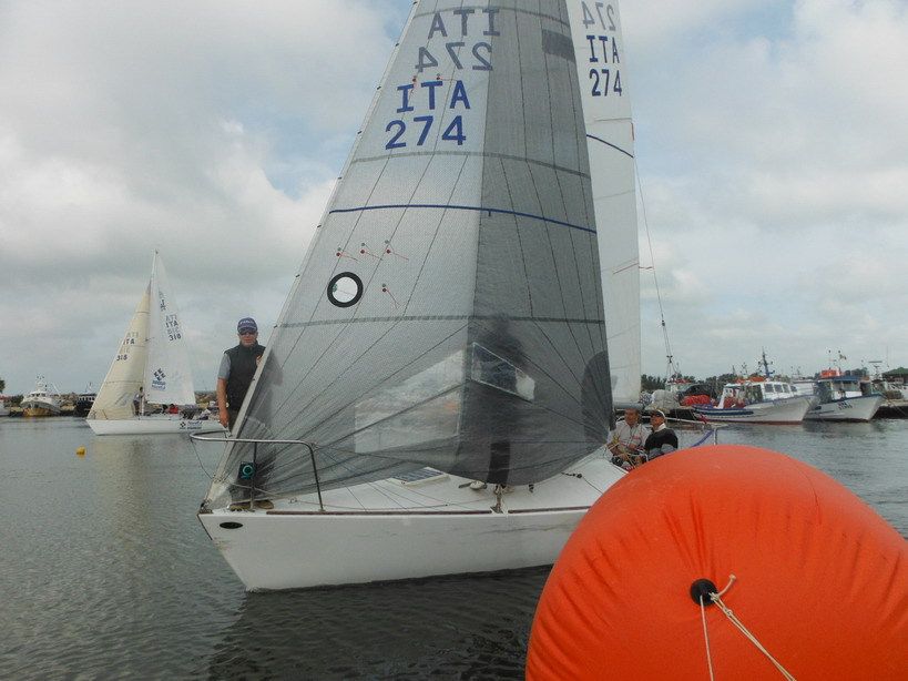 Il J24 L'Armadillo ITA 274 con il genoa grigio passa la boa arancione; dietro il porto peschereccio di Torregrande e un altro J24